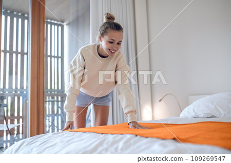 Girl in white making bed in the morning Girl in white making bed in the morning 109269547