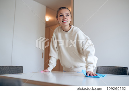 Young girl in white doing cleaning and looking involved Young girl in white doing cleaning and looking involved 109269562