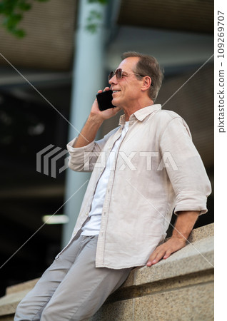 Man posing on street and looking talking by his phone. 109269707