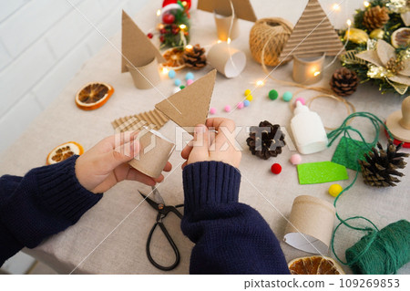 Step-by-step instructions on how to make a Christmas tree out of cardboard. Step 2 connect the upper triangular part with a cardboard roll stand. Zero waste concept. 109269853
