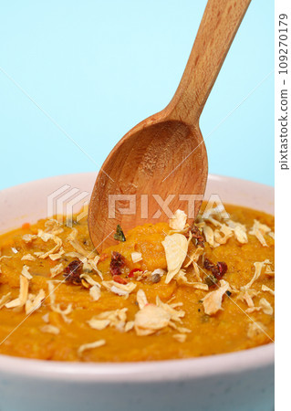 Sweet potato puree in bowl and wooden spoon on blue background, close up 109270179
