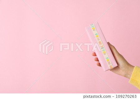 Gift box in female hand on pink background, space for text 109270263