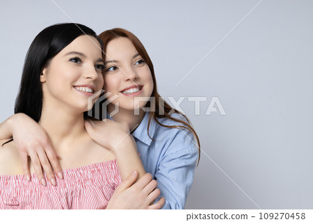 Two sisters pose on a light background 109270458