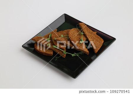Pieces of rye bread on a black plate on a white background 109270541