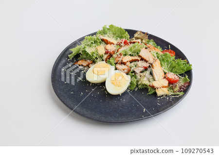 Caesar salad with chicken on a dark flat plate on a white background 109270543