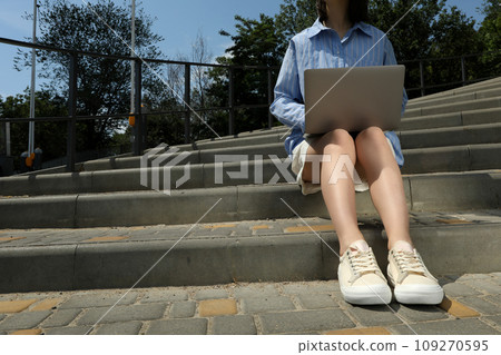 The girl works on a laptop while sitting on the stairs The girl works on a laptop while sitting on the stairs 109270595