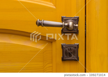 Close-up macro yellow wooden door metal handle object detail indoor 109271014