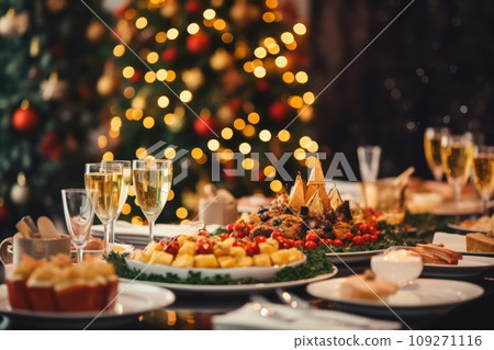 Christmas festive family dinner served different dishes and salads, many snacks, sparkling wine and glasses. New Year's decor with Xmas tree on background. Christmas festive family dinner served different dishes and salads, many snacks, sparkling wine and glasses. New Year's decor with Xmas tree on background. 109271116