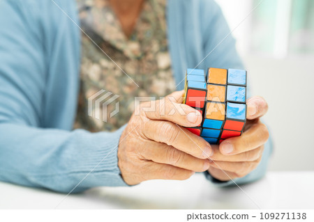 Bangkok, Thailand August 14, 2023 Alzheimer disease AD, Asian elderly woman patient playing Rubik cube game to practice brain training for dementia prevention. 109271138