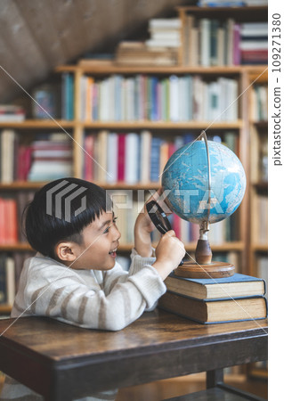 7 year old boy looking at the globe with a magnifying glass 7 year old boy looking at the globe with a magnifying glass 109271380