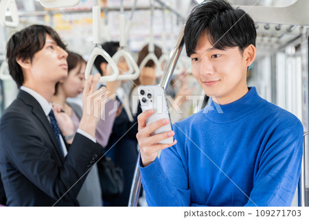 一名大學生在電車上看著智慧型手機。照片由京王電鐵株式會社提供。 109271703