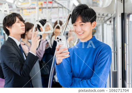 A college student looking at a smartphone on a train. Photo provided by Keio Electric Railway Co., Ltd. 109271704