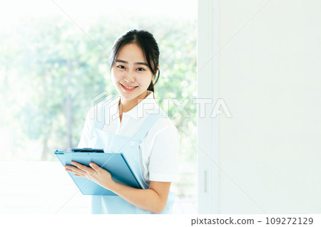 Young female caregiver standing by the window 109272129