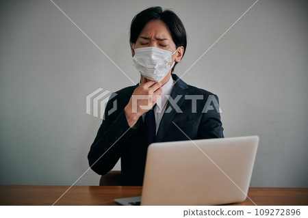 A young male office worker has a sore throat and presses it with his hand 109272896