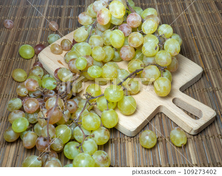 Grapes on the table. Kishmish on a wooden surface. Grapes of different colors on a kitchen board. Wine ingredient. Grapes on the table. Kishmish on a wooden surface. Grapes of different colors on a kitchen board. Wine ingredient. 109273402