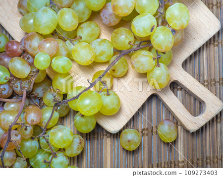 Grapes on the table. Kishmish on a wooden surface. Grapes of different colors on a kitchen board. Wine ingredient. Grapes on the table. Kishmish on a wooden surface. Grapes of different colors on a kitchen board. Wine ingredient. 109273403