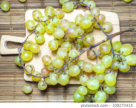 Green variety of grapes on the table. Berry harvest. Home furnishings. Kishmish on the table. Grapes of different colors. Fruit dessert. Wine ingredient. 109273418