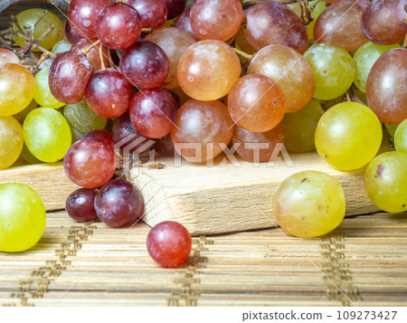 Green variety of grapes on the table. Berry harvest. Home furnishings. Kishmish on the table. Grapes of different colors. Fruit dessert. Wine ingredient. 109273427