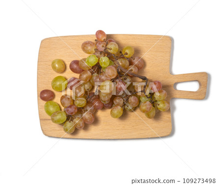 Grapes on the table. White background. Kishmish on a white background. Grapes of different colors on a kitchen board. Wine ingredient. 109273498