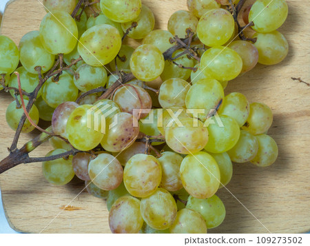 Grapes on the table. White background. Kishmish on a white background. Grapes of different colors on a kitchen board. Wine ingredient. Grapes on the table. White background. Kishmish on a white background. Grapes of different colors on a kitchen board. Wine ingredient. 109273502