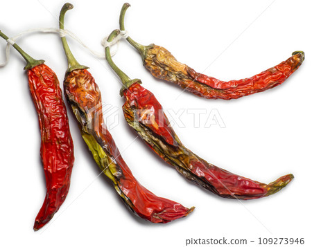 Bunch of dried red peppers on a white background. Spices for dishes. The concept of spicy food. Wrinkled chili pepper. 109273946