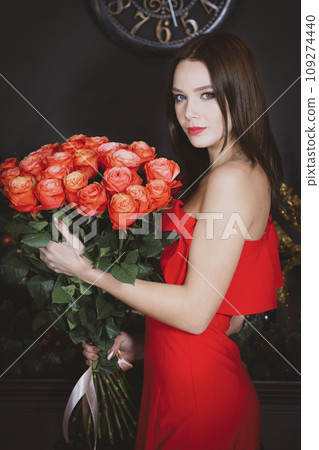 Beautiful girl in a red dress with a bouquet. Vertical. Model woman with roses. Beautiful girl in a red dress with a bouquet. Vertical. Model woman with roses. 109274440