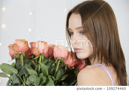 Beautiful face of the model and with a bouquet of roses. Woman with flowers. Beautiful face of the model and with a bouquet of roses. Woman with flowers. 109274460