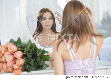 Beautiful girl looks at herself in the mirror. Beautiful girl looks at herself in the mirror. 109274467