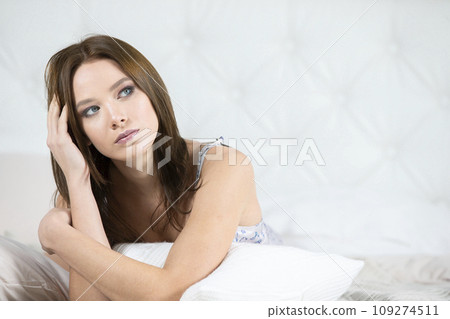 Young girl lies on the bed. Portrait of a beautiful woman in the bedroom Young girl lies on the bed. Portrait of a beautiful woman in the bedroom 109274511