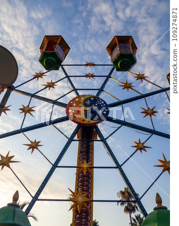 A small Ferris wheel in the park. A bright attraction for children. Entertainment in the park. Colorful booths. High above the ground. Children's fun. Entertainment industry concept. A small Ferris wheel in the park. A bright attraction for children. Entertainment in the park. Colorful booths. High above the ground. Children's fun. Entertainment industry concept. 109274871