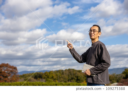 Mature man standing outdoors with a tablet 109275388