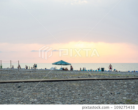 Resort place. Umbrellas and sunbeds on the beach. Coastline. Beach at sunset. Beach business. People on vacation. 109275438