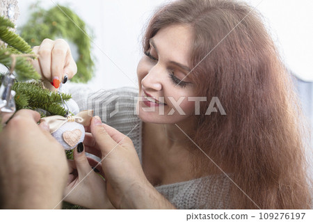 Decorating a Christmas tree. A girl and a man's hands hang Christmas tree decorations. Decorating a Christmas tree. A girl and a man's hands hang Christmas tree decorations. 109276197