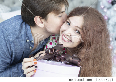Beautiful couple with christmas present. New Year's holidays. Man and woman with a festive box. Beautiful couple with christmas present. New Year's holidays. Man and woman with a festive box. 109276741
