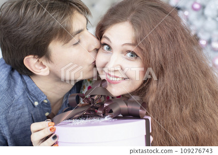 Beautiful couple with christmas present. New Year's holidays. Man and woman with a festive box. Beautiful couple with christmas present. New Year's holidays. Man and woman with a festive box. 109276743