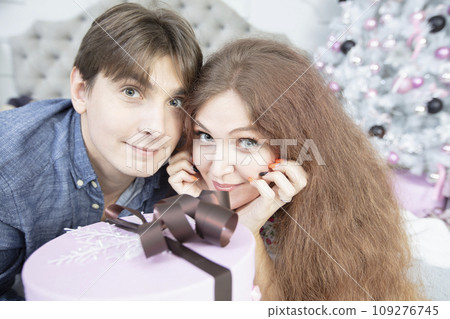Beautiful couple with christmas present. New Year's holidays. Man and woman with a festive box. Beautiful couple with christmas present. New Year's holidays. Man and woman with a festive box. 109276745