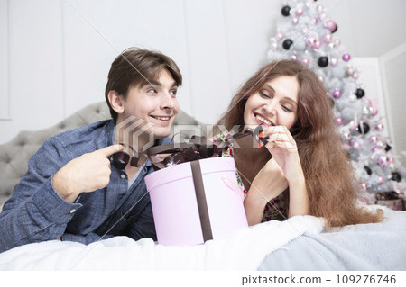 Beautiful couple with christmas present. New Year's holidays. Man and woman with a festive box. Beautiful couple with christmas present. New Year's holidays. Man and woman with a festive box. 109276746