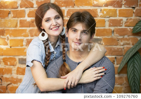 Portrait of a young couple on a brick wall background Portrait of a young couple on a brick wall background 109276760