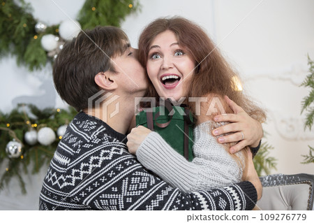 A man gives a woman a Christmas present. Husband and wife in the New Year holidays. Get a surprise in the winter holidays. Christmas holidays concept. 109276779