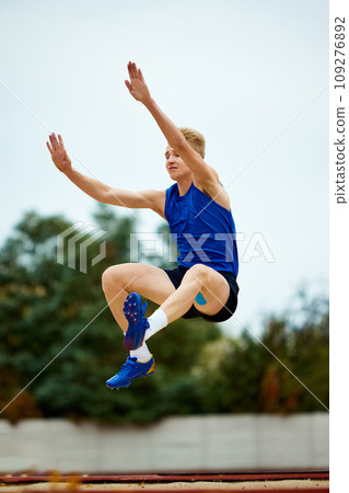 Synergy of strength and technique embodied in single jump. Professional, skilled sportsman, runner's descent into awaiting sand 109276892