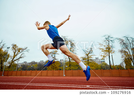 Dynamic steps leading to an impactful long jump. Bottom view full length portrait of professional sportsman running on sport field. Dynamic steps leading to an impactful long jump. Bottom view full length portrait of professional sportsman running on sport field. 109276916