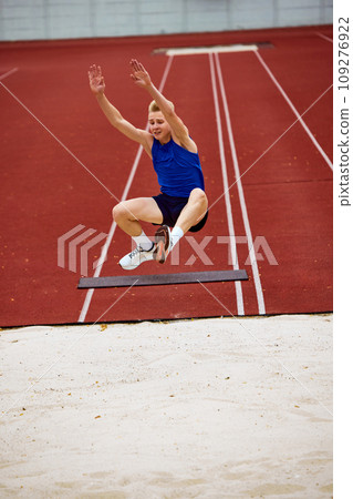 Determination evident in running long jump. Athletic man, sportsman frozen in air, following rules, completed perfect long jump. 109276922