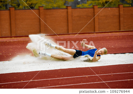 Energetic long jump showcased in a captivating frame. Portrait of athletic young man have long jumping competition. Energetic long jump showcased in a captivating frame. Portrait of athletic young man have long jumping competition. 109276944