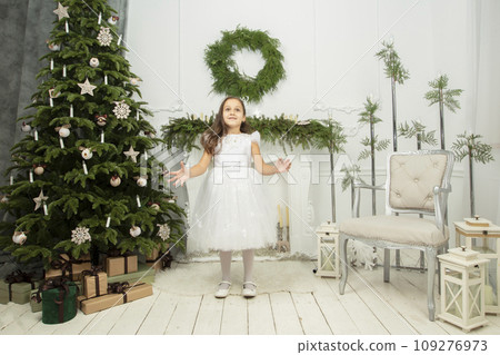 Elegant child at the Christmas tree. Little joyful girl in christmas 109276973