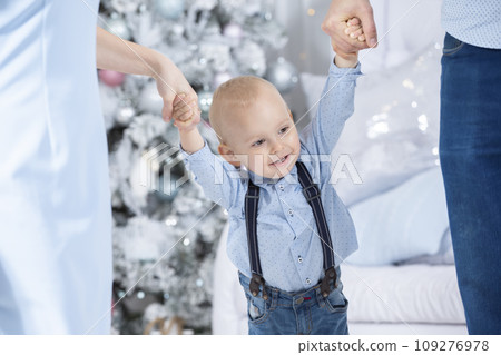 New year and Christmas. Mom and dad are holding the hands of a young son on the background of a Christmas tree 109276978