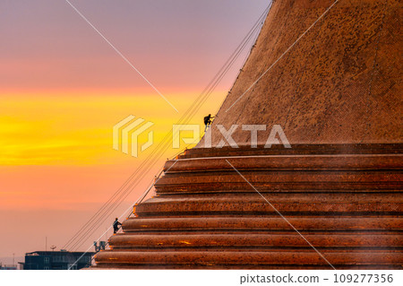 Buddhists climb up to light decoration the golden pagoda Phra Pathom Chedi on sunset sky in annual festive at Nakhon Pathom 109277356