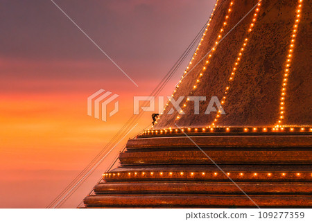 Buddhists climb up to light decoration the golden pagoda Phra Pathom Chedi on sunset sky in annual festive at Nakhon Pathom 109277359
