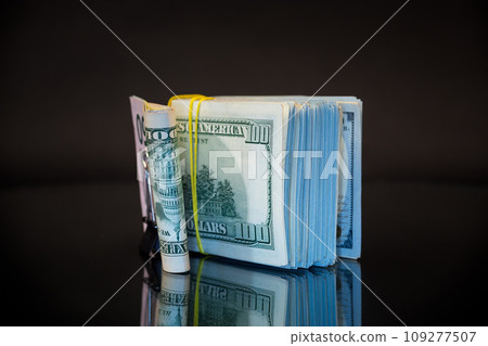 stack of dollar bills collected in an elastic band and a stationery clip 109277507