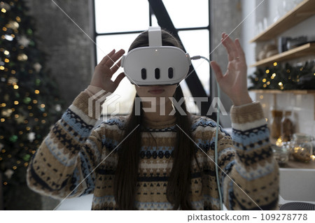 The Christmas kitchen is where a stylish and beautiful girl cooks following a recipe using a virtual reality headset. The Christmas kitchen is where a stylish and beautiful girl cooks following a recipe using a virtual reality headset. 109278778