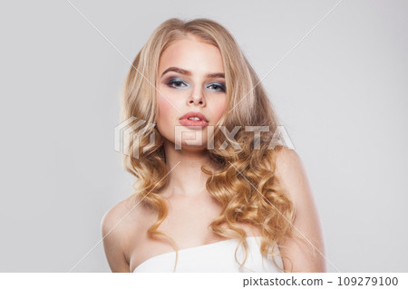 Lovely female face. Blonde woman with long curly hair and makeup studio portrait 109279100
